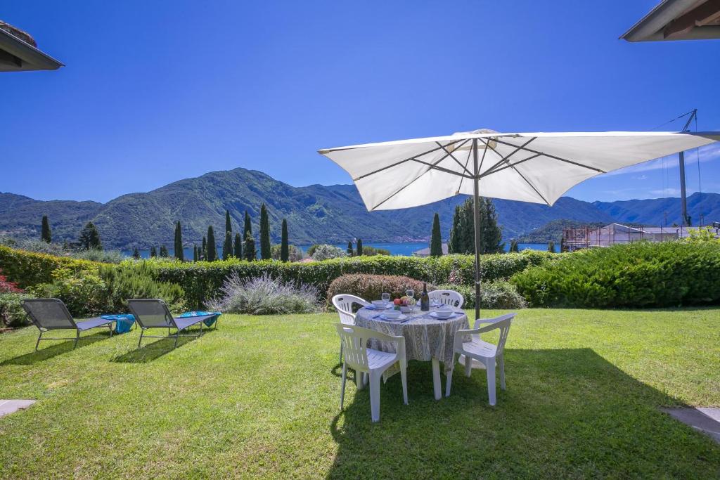 a table and chairs under an umbrella in a yard at Villa Paola Tremezzo in Tremezzo