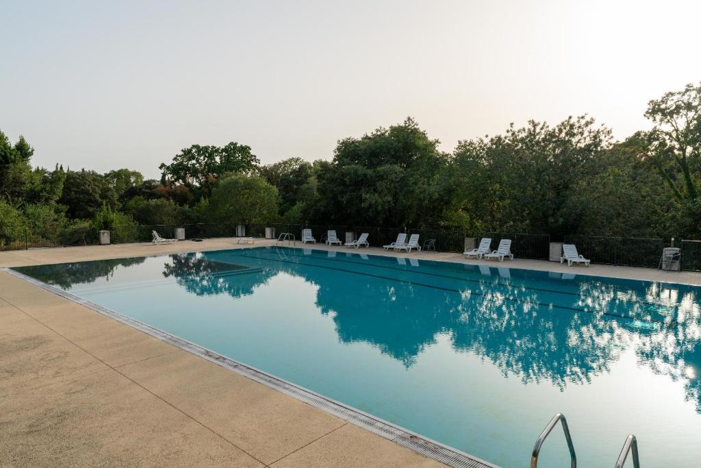 una gran piscina con sillas y árboles en Studio Camargue en Nimes