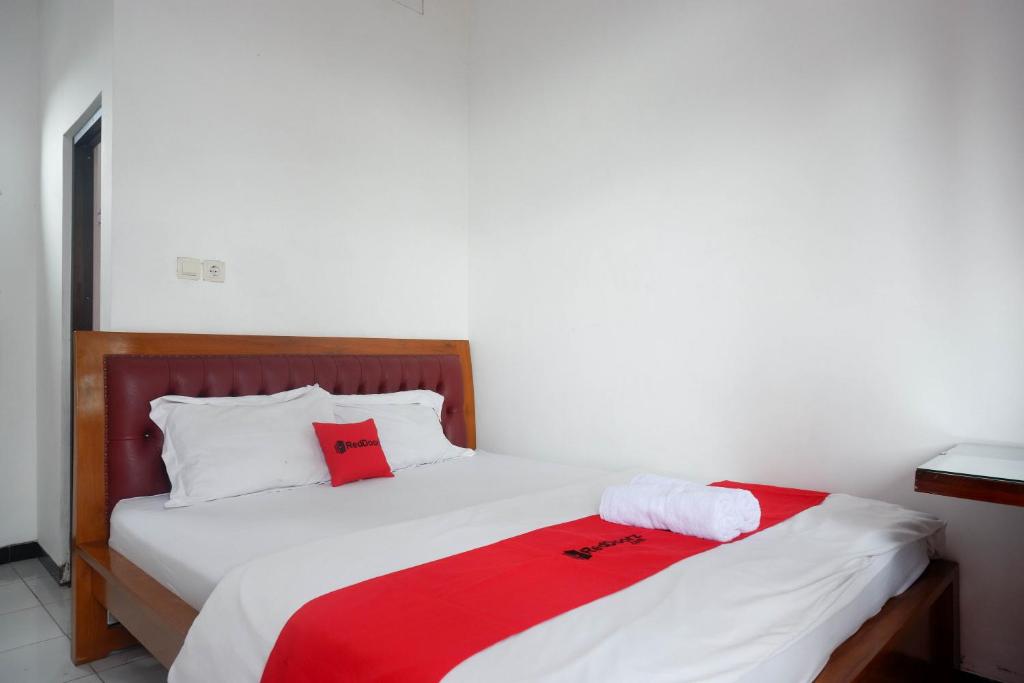 - une chambre dotée d'un lit avec une couverture rouge et blanche dans l'établissement RedDoorz near Alun Alun Wonosobo 2, à Wonosobo