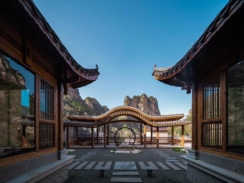 una entrada a un edificio con montañas en el fondo en 雾里观阵山 Foggy Valley en Zhangjiajie