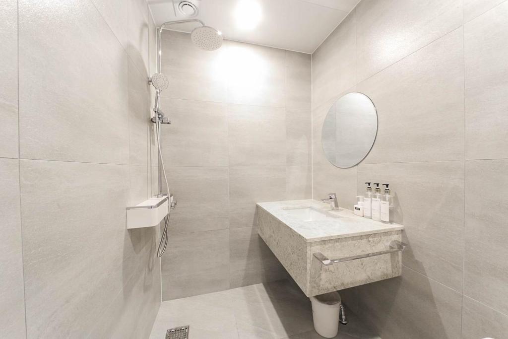 a white bathroom with a sink and a mirror at Bonatree Hotel in Busan