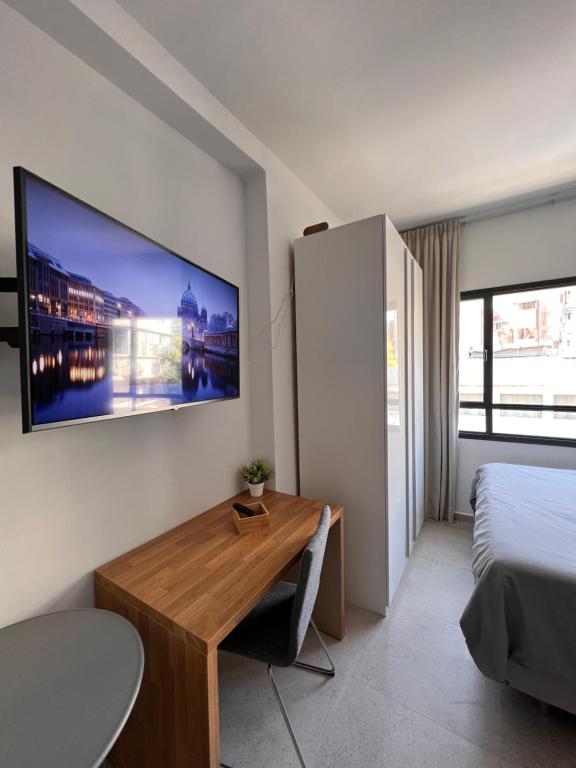 a bedroom with a desk and a tv on the wall at White Door Apartments in Haifa