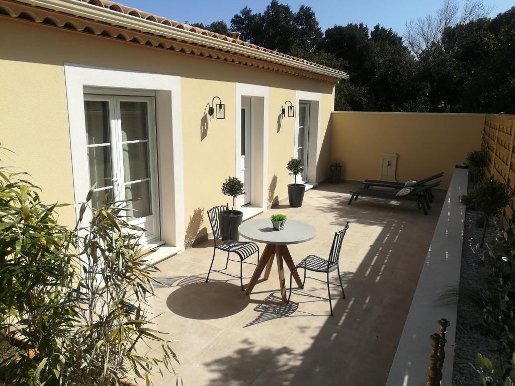 eine Terrasse mit einem Tisch und Stühlen sowie ein Gebäude in der Unterkunft Le Mazet d'Olivia, escapade romantique en Provence in Châteauneuf-de-Gadagne