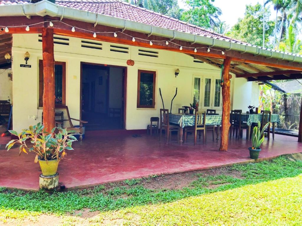 a house with a covered patio with tables and chairs at Hiriketiya Green Hill Home in Dickwella