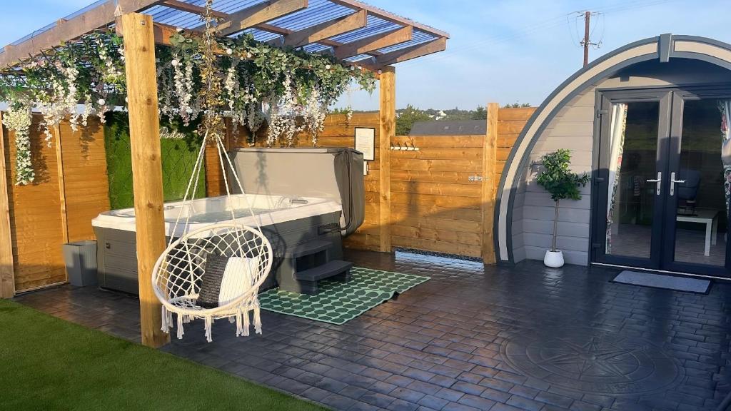a patio with a grill and a swing at The Garden Pod with Private Hot Tub in Ballymagan