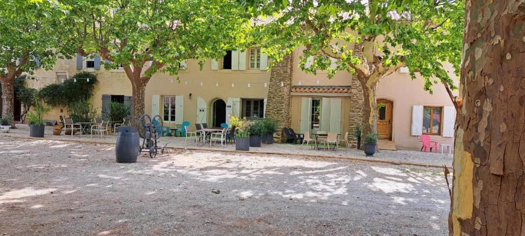 a building with trees and tables and chairs in front of it at Chateau Le Vergel Authenac in Ginestas