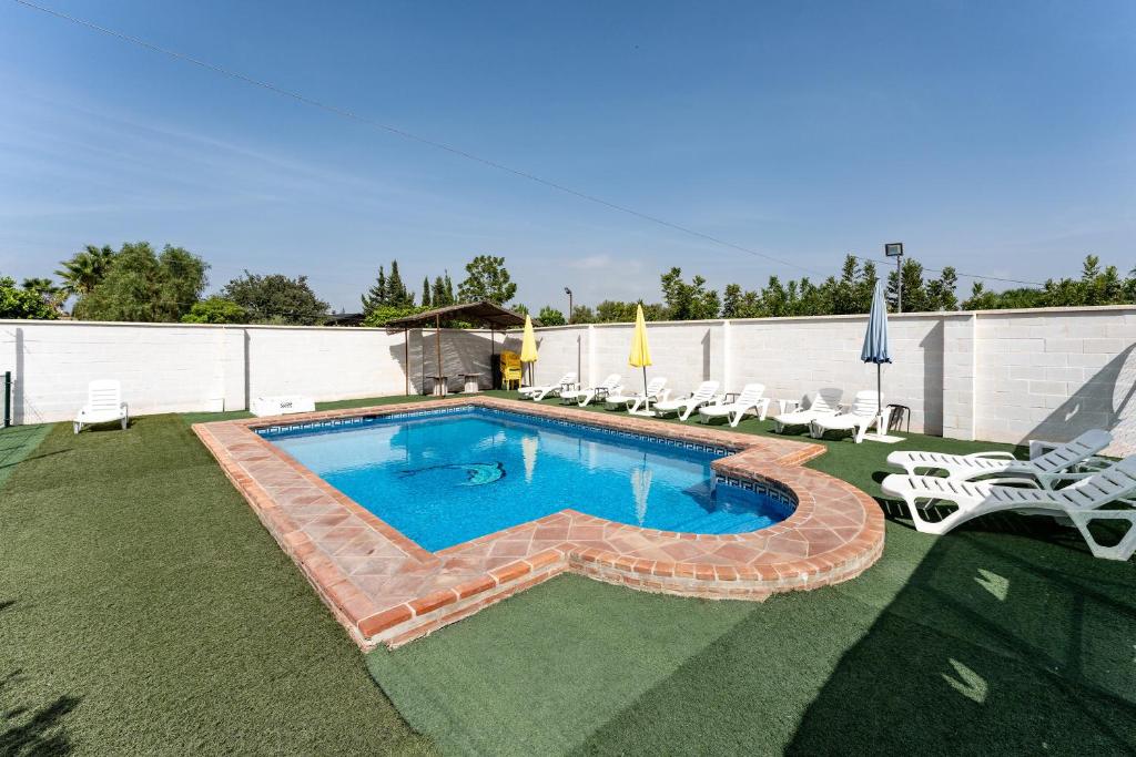 una piscina en un patio con sillas en La Casa de los Recuerdos, en Villafranco de Guadalhorce