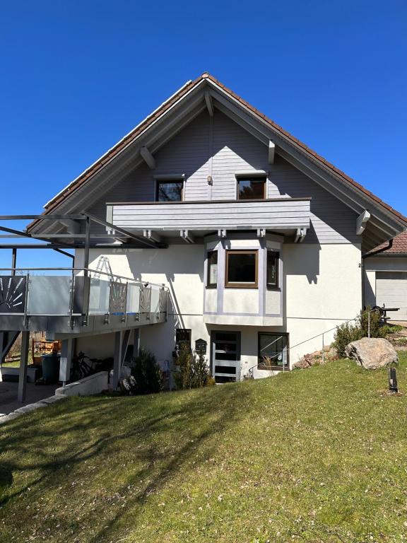 a white house with a balcony and a yard at Ferienwohnung Steinhart Kappel in Lenzkirch