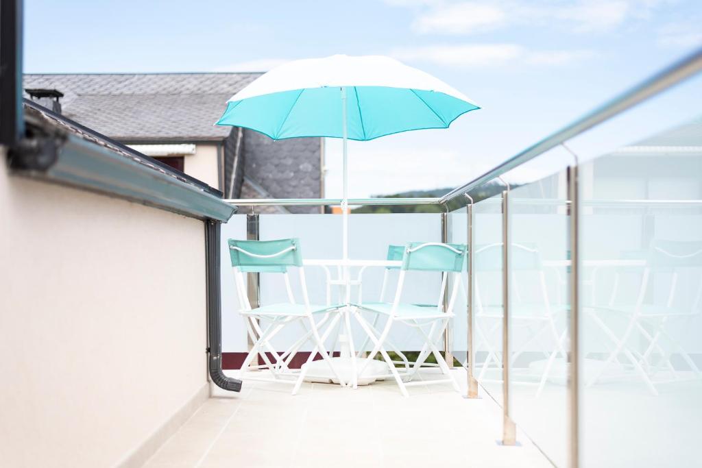 einen Balkon mit 2 Stühlen und einem Sonnenschirm in der Unterkunft Apartamento Las Candelas, Ares in Ares