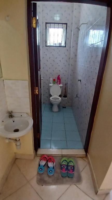 een badkamer met een toilet en twee paar schoenen bij AirBnB one bedroom at Bamburi-Mwembeni Mombasa in Mombasa