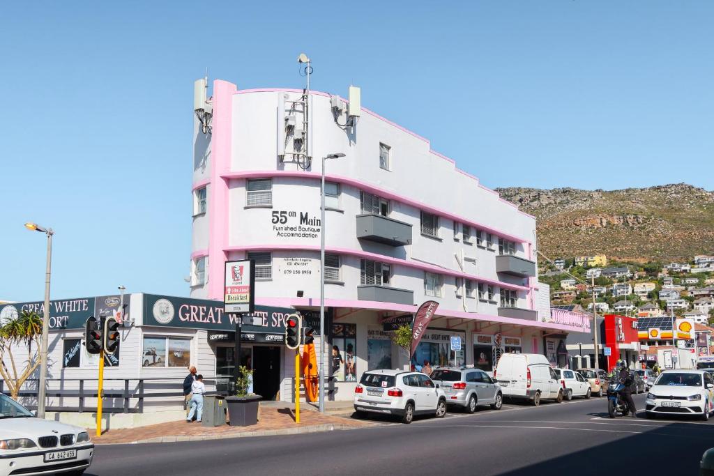 a pink building with cars parked in front of a street at 55 on Main in Fish hoek