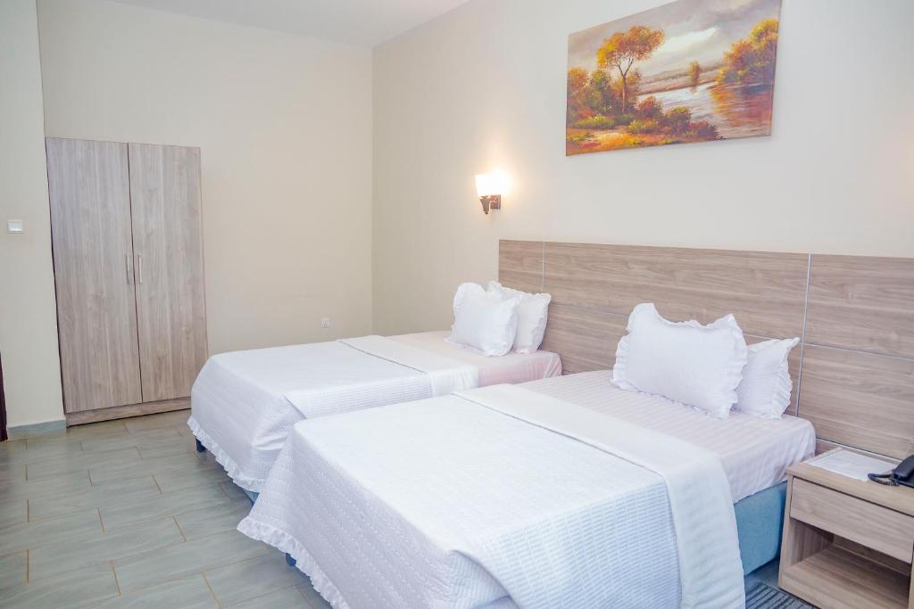 um quarto de hotel com duas camas e um quadro na parede em Baobab Hotel LTD em Kigali