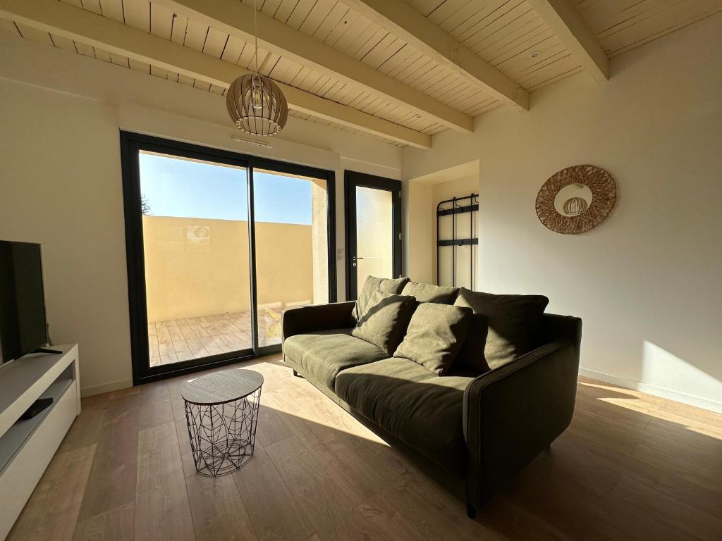 - un salon avec un canapé et une grande fenêtre dans l'établissement La Halte Occitane - Logement neuf 6 personnes 3 chambres tout confort, à Montauban