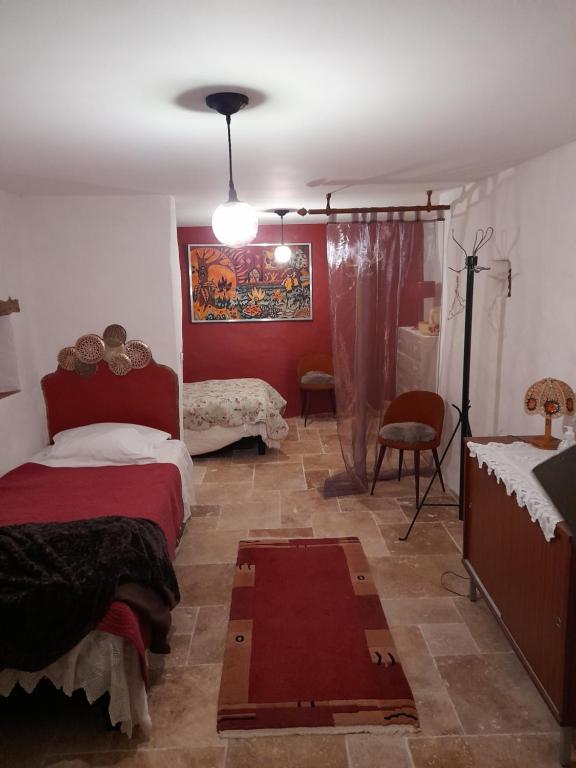 - une chambre avec 2 lits et un mur rouge dans l'établissement Sur le chemin, à Auvillar