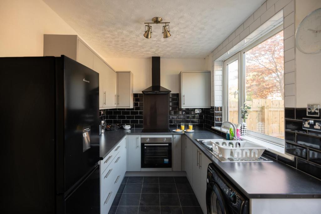 cocina con nevera negra y fregadero en Brinkburn House By Horizon Stays, en Stockton-on-Tees