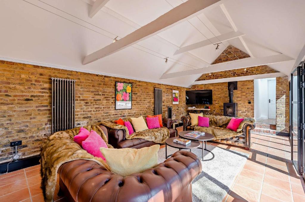 a living room with leather furniture and a brick wall at The Willows by Bloom Stays in Ash