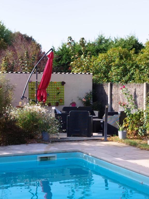 a swimming pool with a red umbrella in a yard at Chambre in Montech