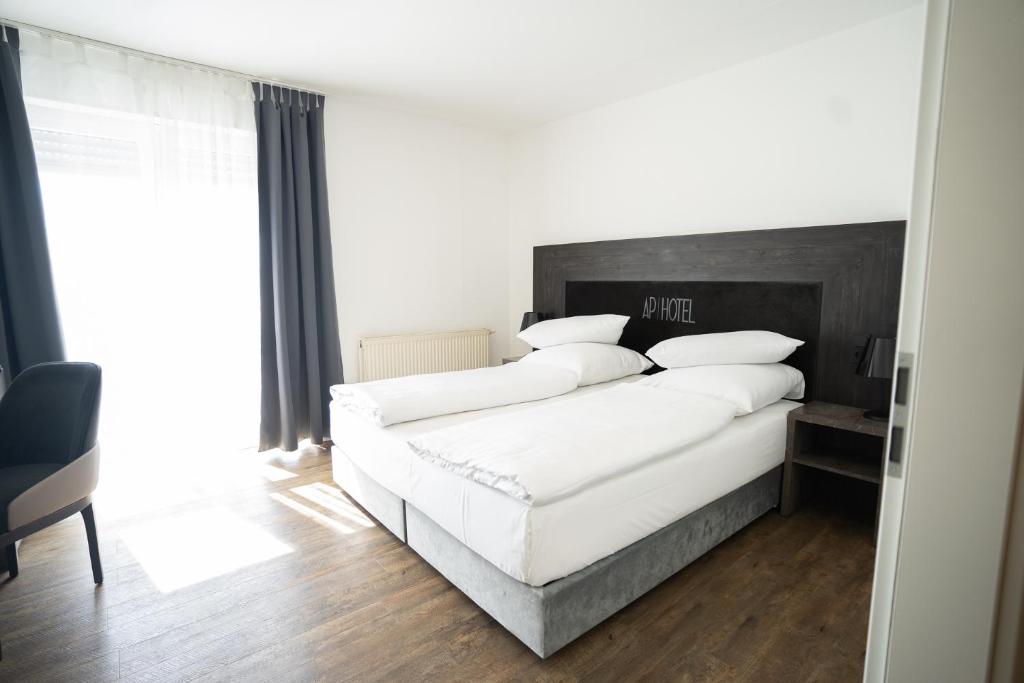 1 dormitorio con 1 cama blanca grande con almohadas blancas en AP Hotel Mannheim Viernheim en Viernheim