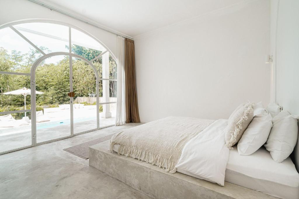 ein weißes Schlafzimmer mit einem Bett und einem großen Fenster in der Unterkunft NEW Jungleview Villa Canggu 3bedroom in Canggu