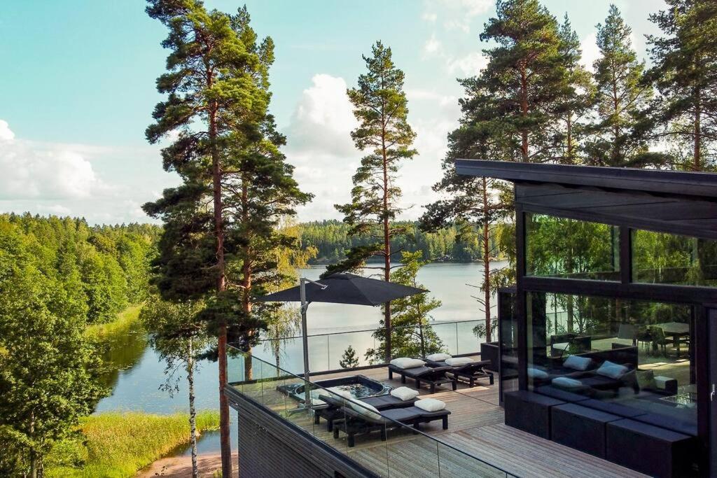 uma casa com um deque com vista para um lago em Villa Padel - Premium Lakeside Residence & Grounds em Lohja