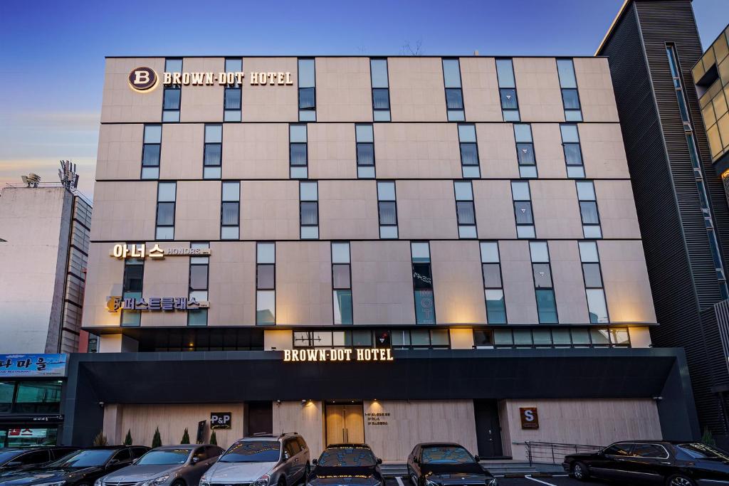 a building with cars parked in a parking lot at Brown Dot Hotel Daegu Suseong in Daegu