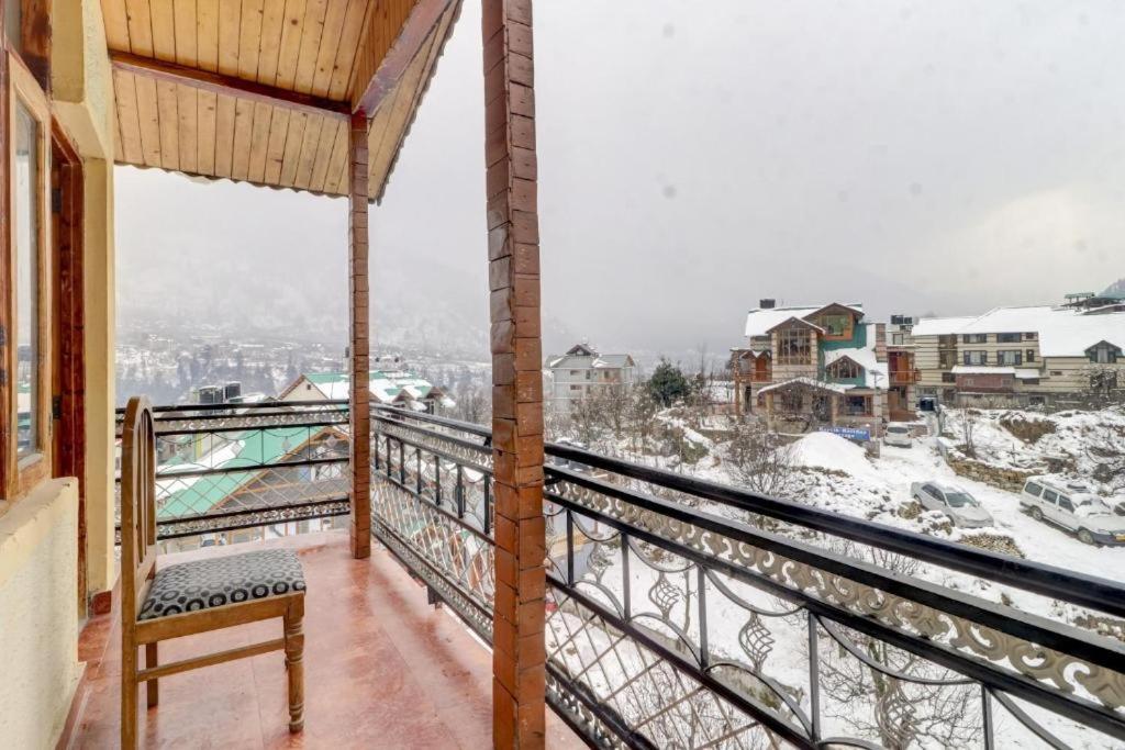 a balcony with a bench and a snow covered city at The Cozy Nook - Manali in Manāli