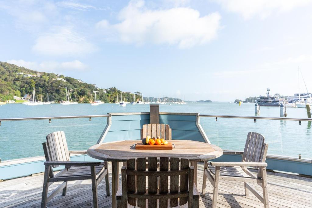 een houten tafel en stoelen op een steiger met een boot bij Bay of Islands 2 Bedrooms On The Water-The Landing in Opua