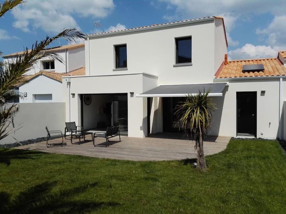 een wit huis met 2 stoelen en een patio bij Maison à 100m de la Mer in Saint-Hilaire-de-Riez