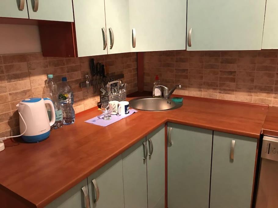 a kitchen counter with a sink and white cabinets at Przytulny apartament z bezpłatnym parkingiem in Olsztyn