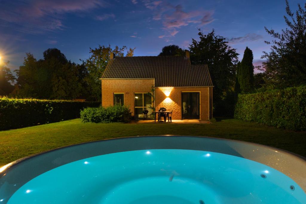 una casa con piscina frente a ella en 6P Vrijstaand Huis met royale tuin en Hottub, en Ewijk