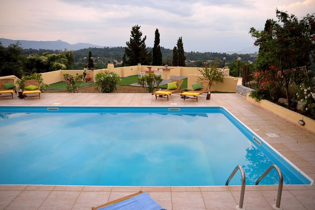 a large swimming pool with chairs and a patio at Melitta Villa in Ágios Ioánnis