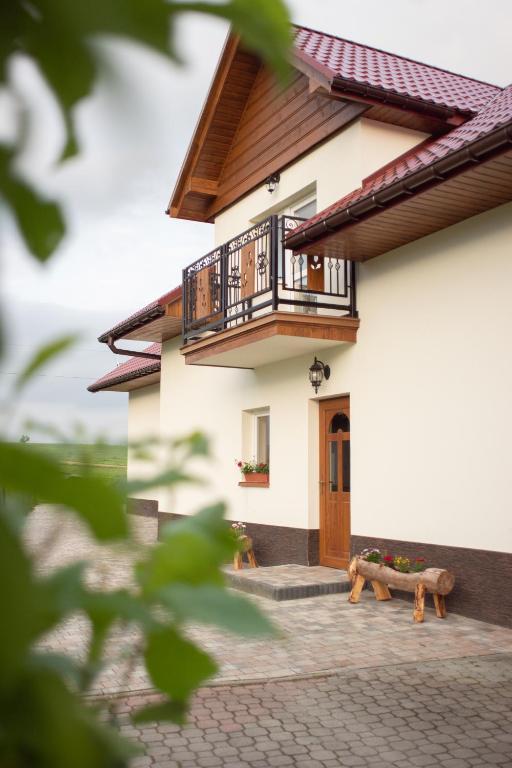 a house with a balcony and a bench in front of it at Zubrzyckie Pokoje in Zubrzyca Dolna