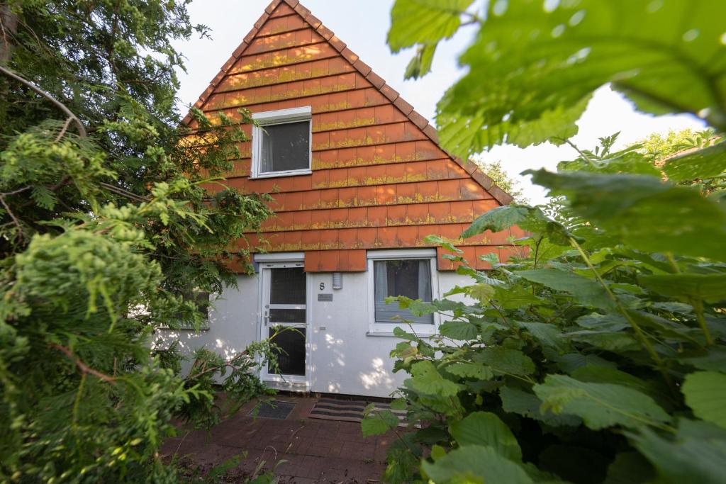 una casa con techo naranja y puerta blanca en VS 8 - Störtebeker Komfort en Dorum Neufeld
