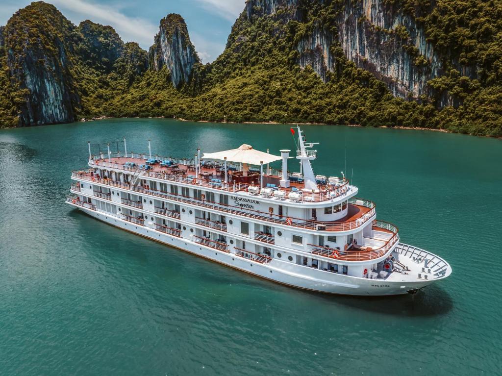 un crucero en el agua con montañas al fondo en AMBASSADOR SIGNATURE CRUISE - Lan Ha Bay, en Ha Long