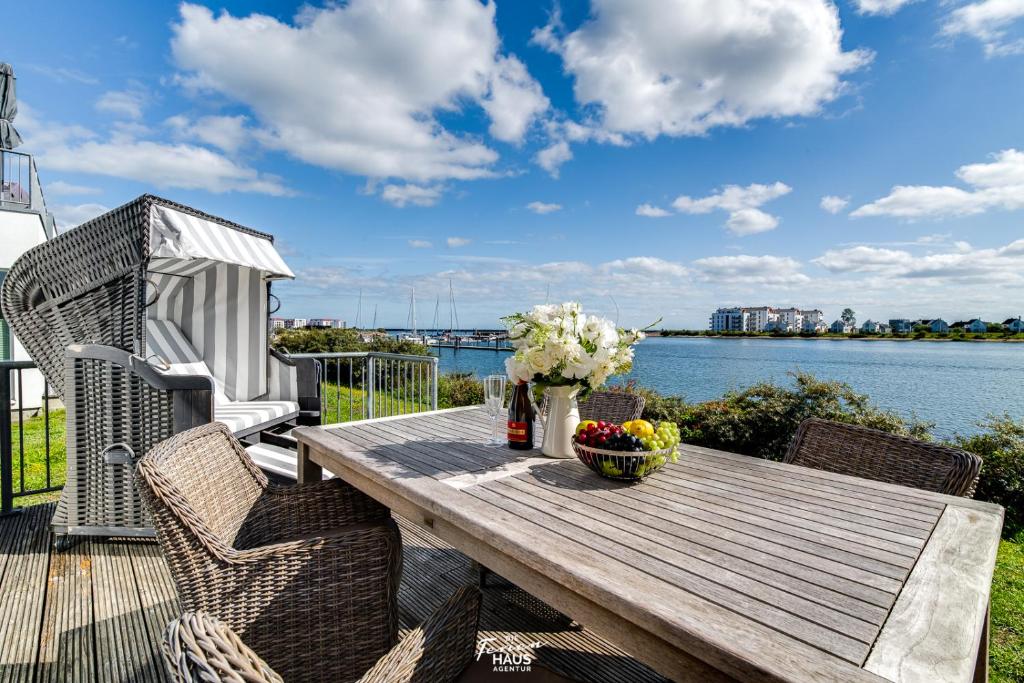 a wooden table on a deck with a view of the water at Am Yachthafen in Olpenitz