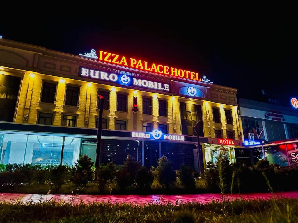 a building with a pizza palace hotel at night at Izza Palace FAST WI-FI 120 MBPS in Tashkent
