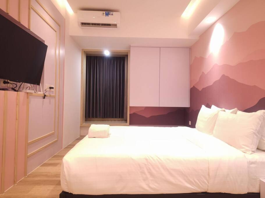 um quarto com uma grande cama branca e uma televisão em Pinky Rose @Anderson Apartment em Surabaya