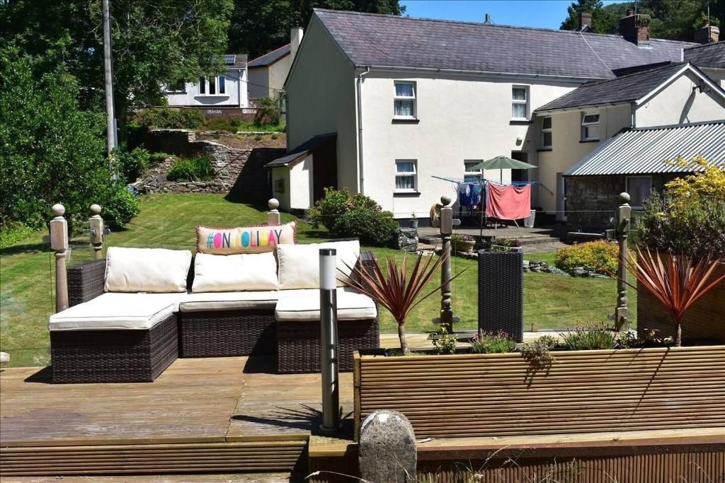 a couch sitting on a wooden deck in a yard at Luxury 2-Bed Cottage in Llansteffan in Carmarthen