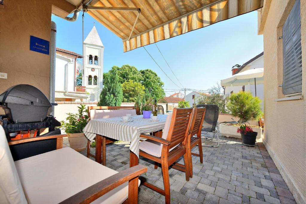 un patio avec une table, des chaises et un grill dans l'établissement Apartments Karla & Marija, à Petrčane