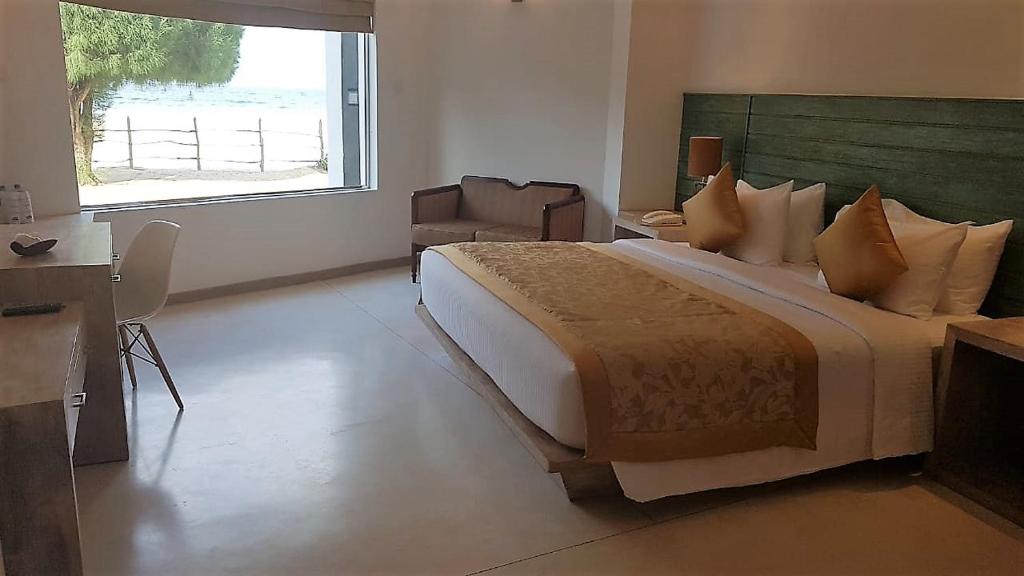 1 dormitorio con 1 cama grande y ventana grande en Nilaveli Beach Hotel, en Nilaveli