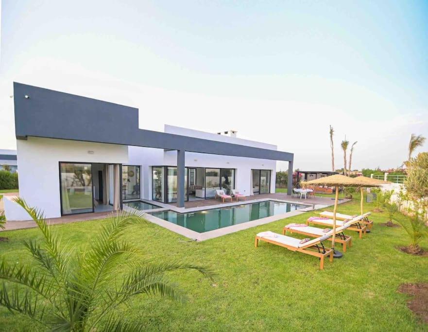 uma casa grande com uma piscina e um quintal em Villa Alanaé avec piscine chauffée em Marrakech
