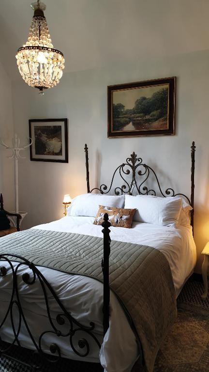 a bedroom with a large bed with a chandelier at Janitor's Lodge in Ticehurst