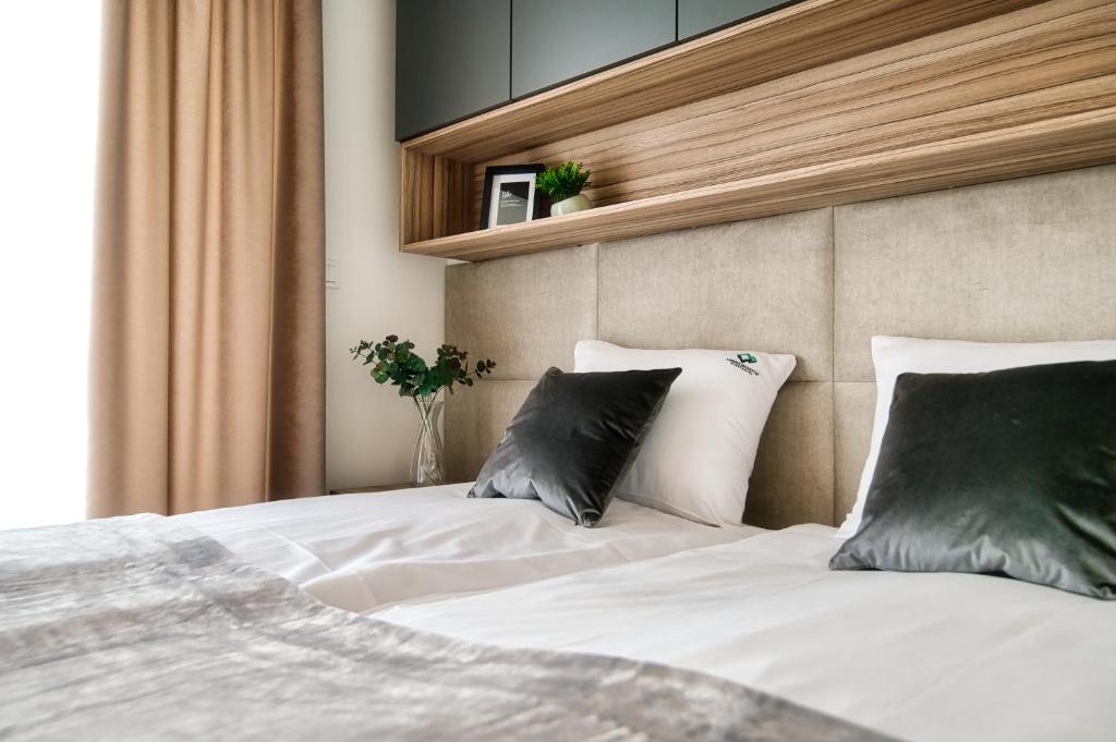 - une chambre avec un lit doté de draps blancs et d'oreillers gris dans l'établissement Apartamenty Laguna Beskidów - A95, à Zarzecze