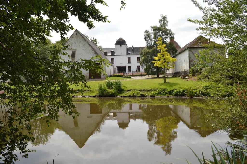 uma vista de uma casa do outro lado de um lago em Le domaine du château blanc à 10 minutes de Paira Daiza em Jurbise