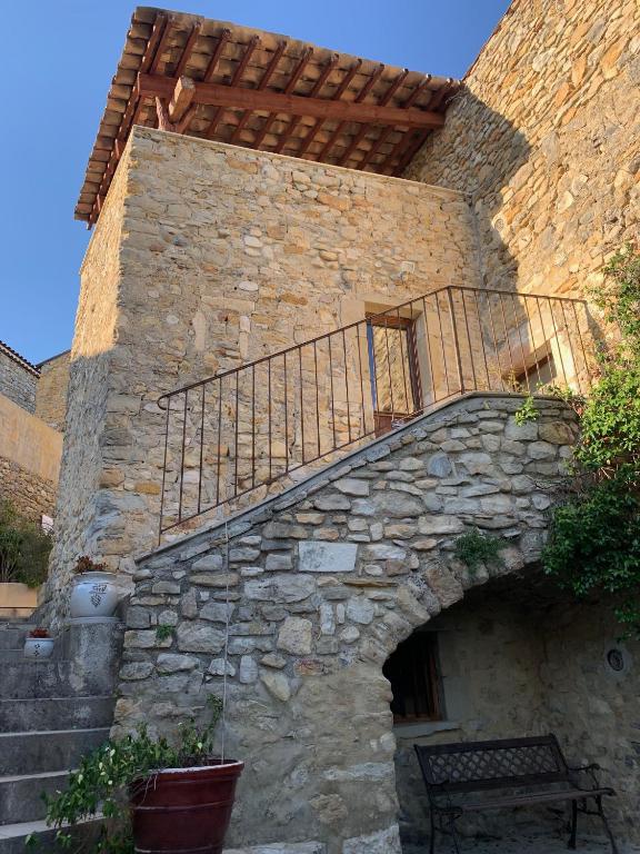 un bâtiment en pierre avec un escalier et un balcon. dans l'établissement LA CONFISERIE, à Saint-Sauveur-de-Cruzières