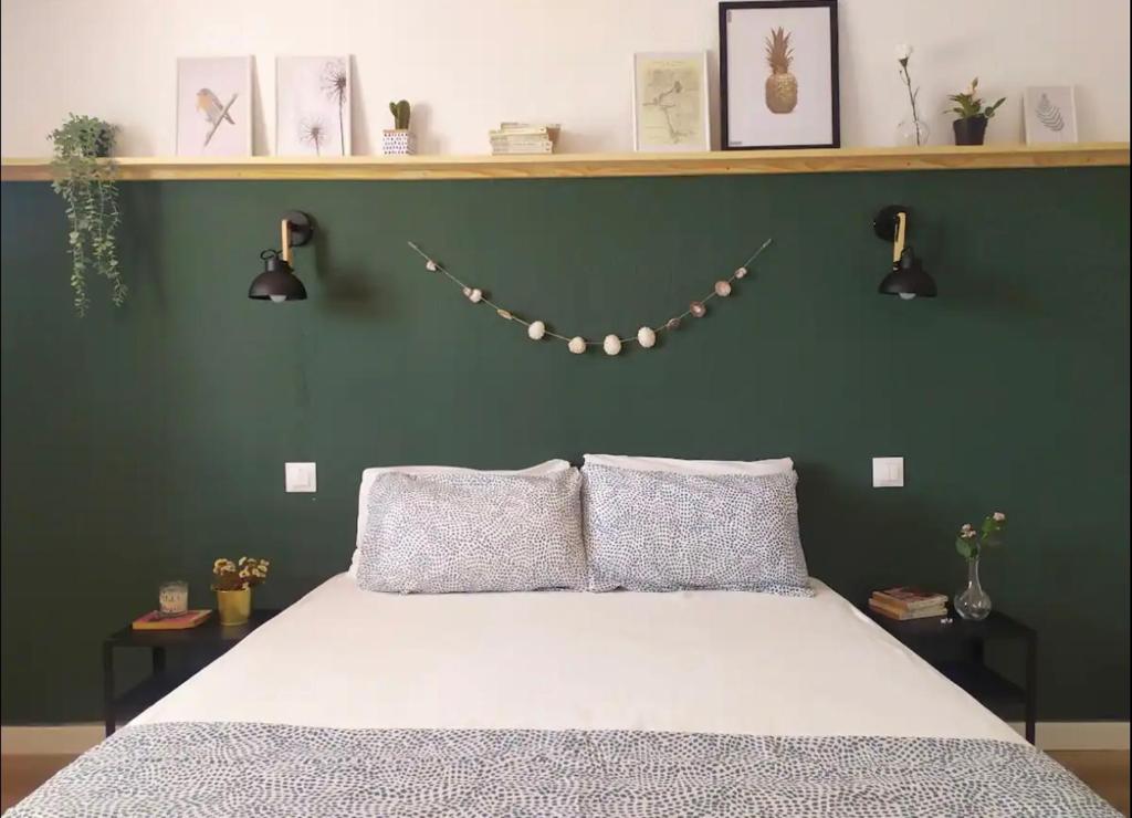 - une chambre avec un lit et un mur vert éclairé dans l'établissement Coqueto apartamento a un minuto de Cala Blanca, à Cala Blanca