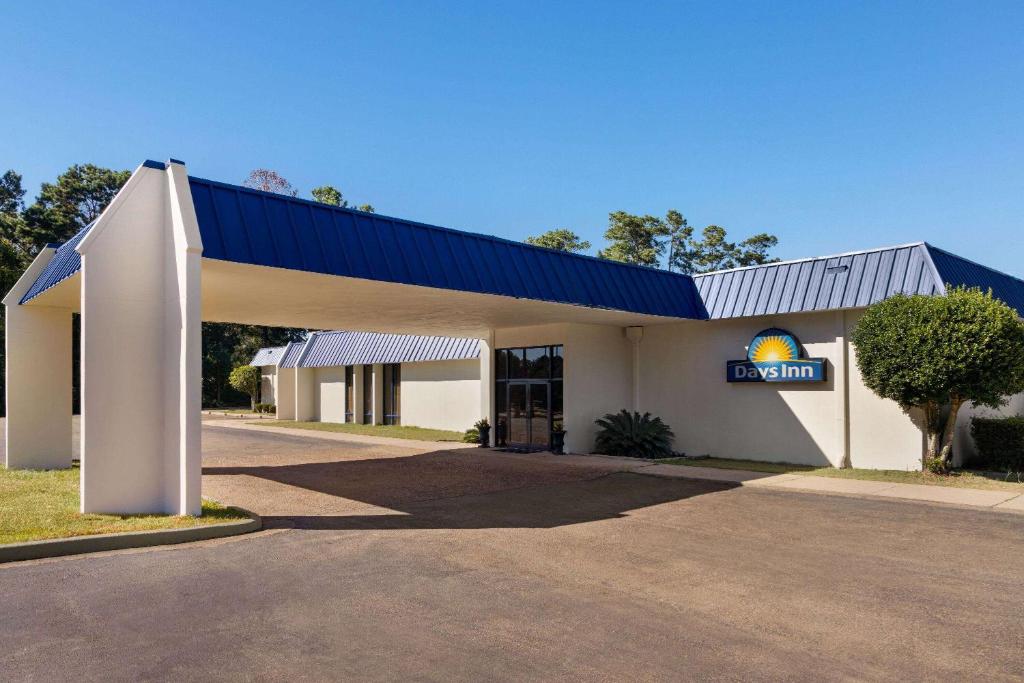 a gas station with a building with a blue roof at Days Inn by Wyndham McComb MS in McComb