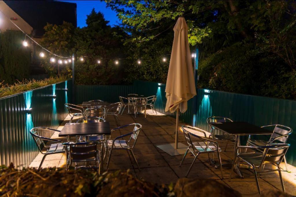 a patio with tables and chairs and an umbrella at Kirkhouse Inn in Milngavie