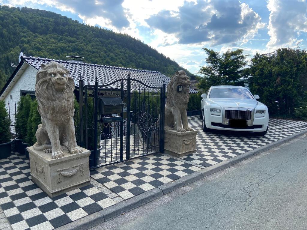 een auto geparkeerd naast een hek met leeuwenbeelden bij VIP Haus Winterberg in Winterberg