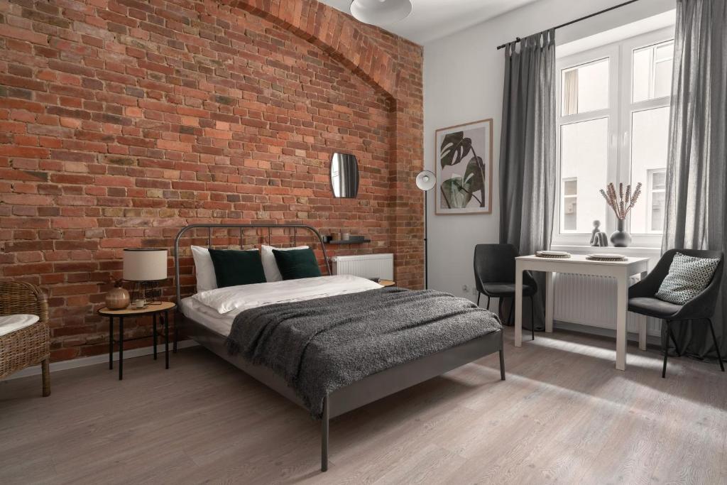 um quarto com uma cama e uma parede de tijolos em HARBOR APARTMENTS - Damrota em Katowice